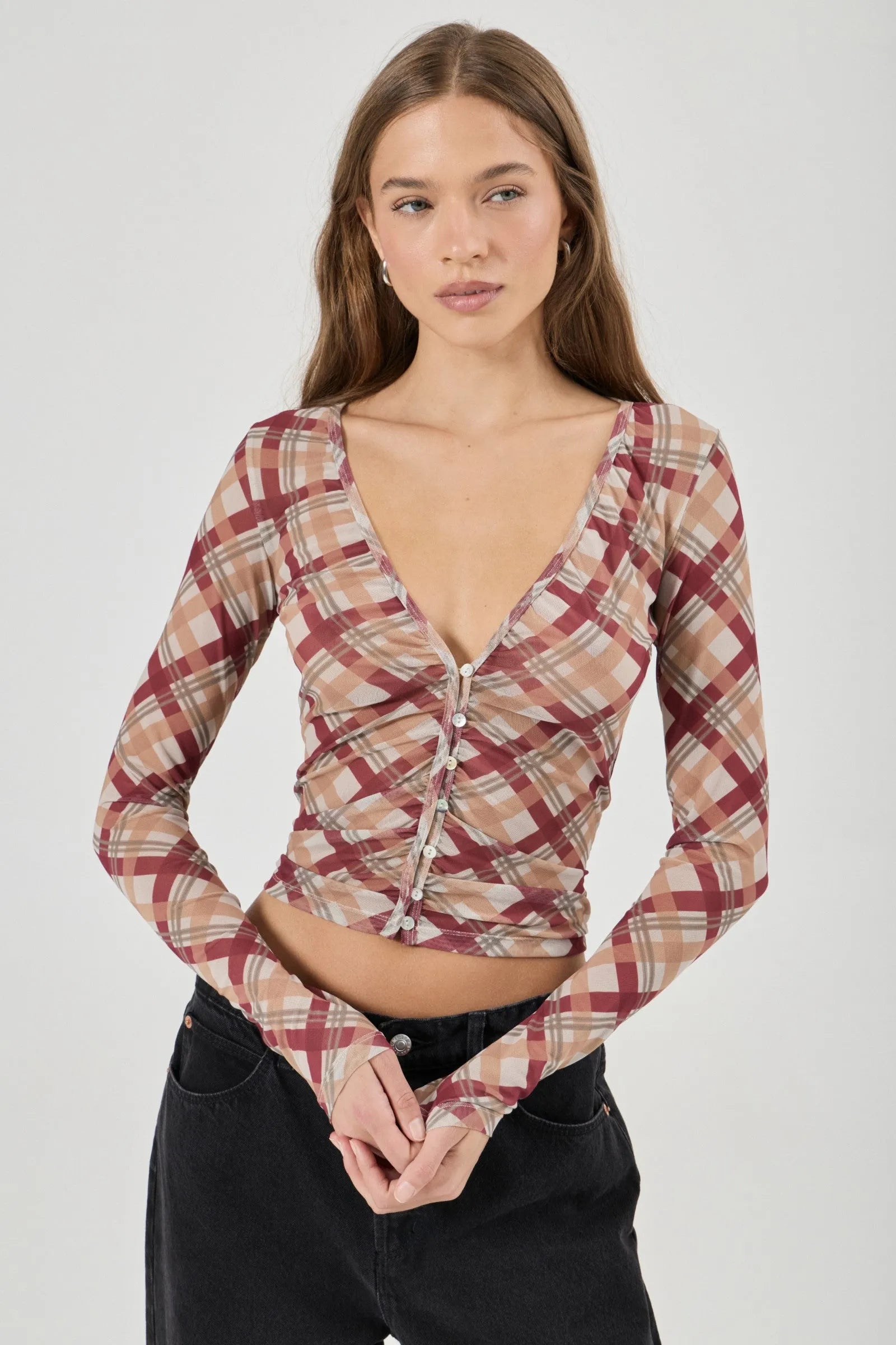 Woman wearing a plaid long-sleeve top against a white background
