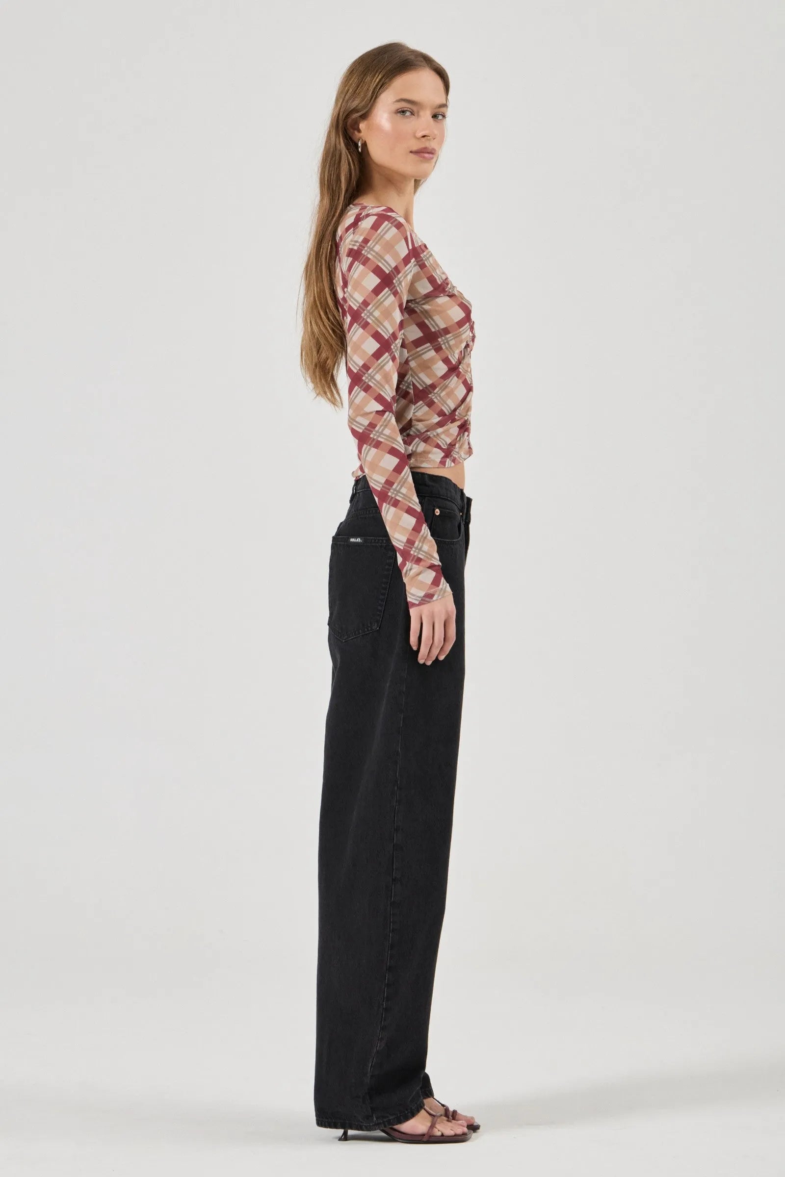 Woman wearing a patterned top and black pants on a white background