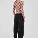 Person wearing a plaid long-sleeve top and black pants on a white background