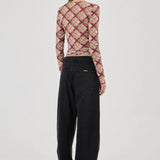 Person wearing a plaid long-sleeve top and black pants on a white background