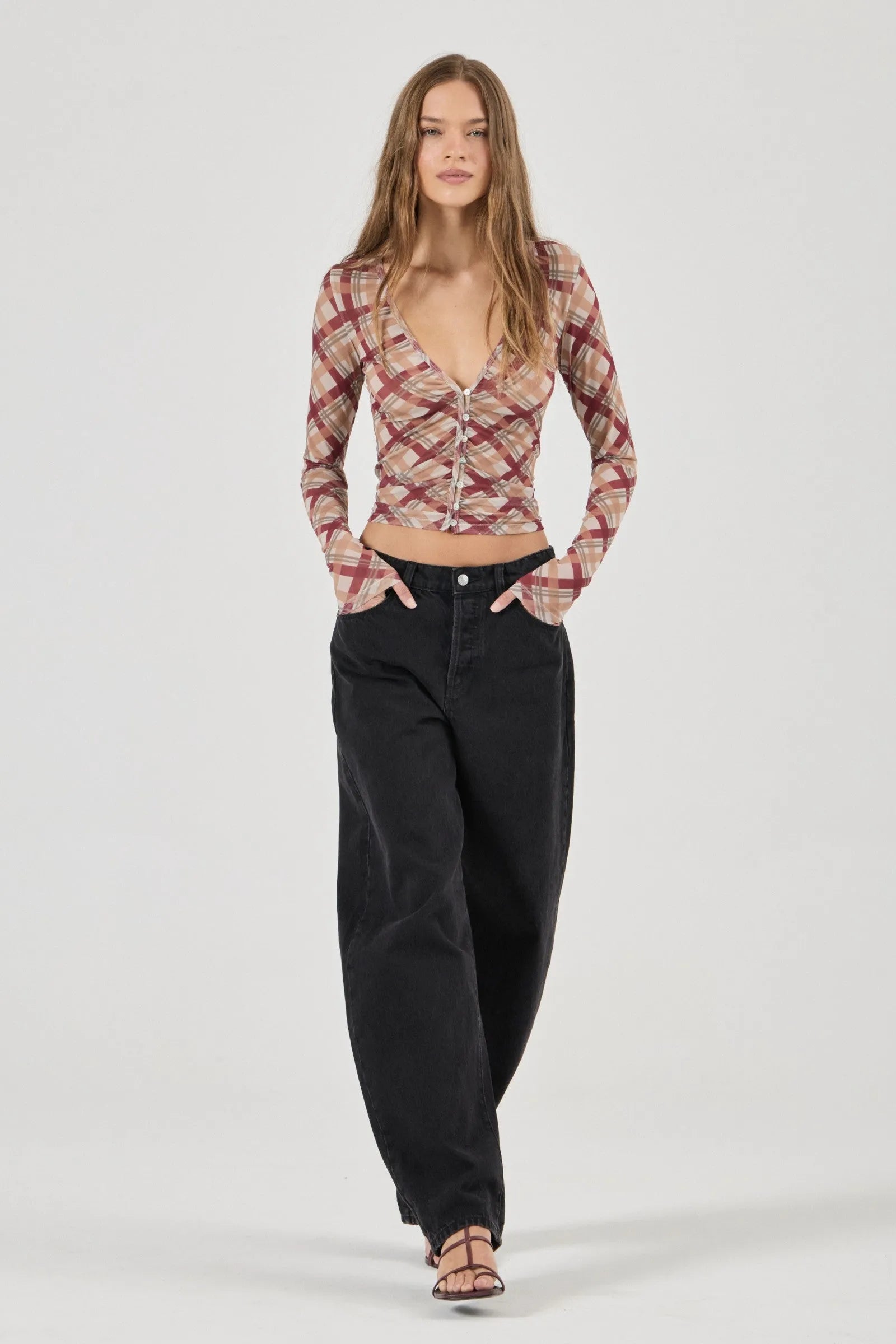 Woman wearing a patterned top and black pants on a white background