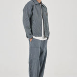 Man wearing a gray jacket and pants on a white background