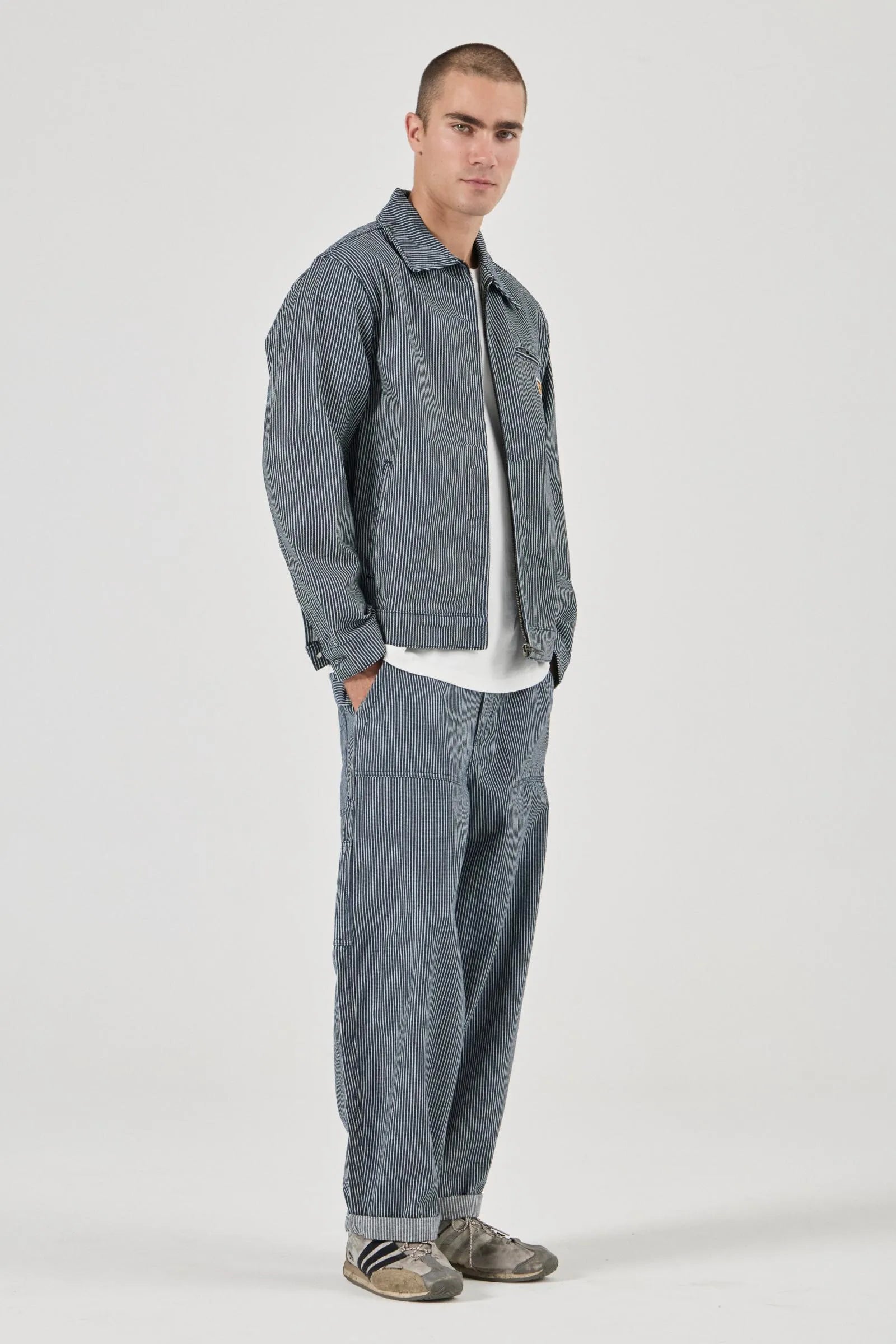 Man wearing a gray jacket and pants on a white background