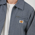 Close-up of a person wearing a striped jacket with a brand logo on a light gray background