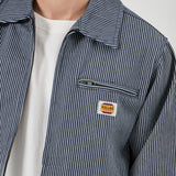 Close-up of a person wearing a striped jacket with a brand logo on a light gray background