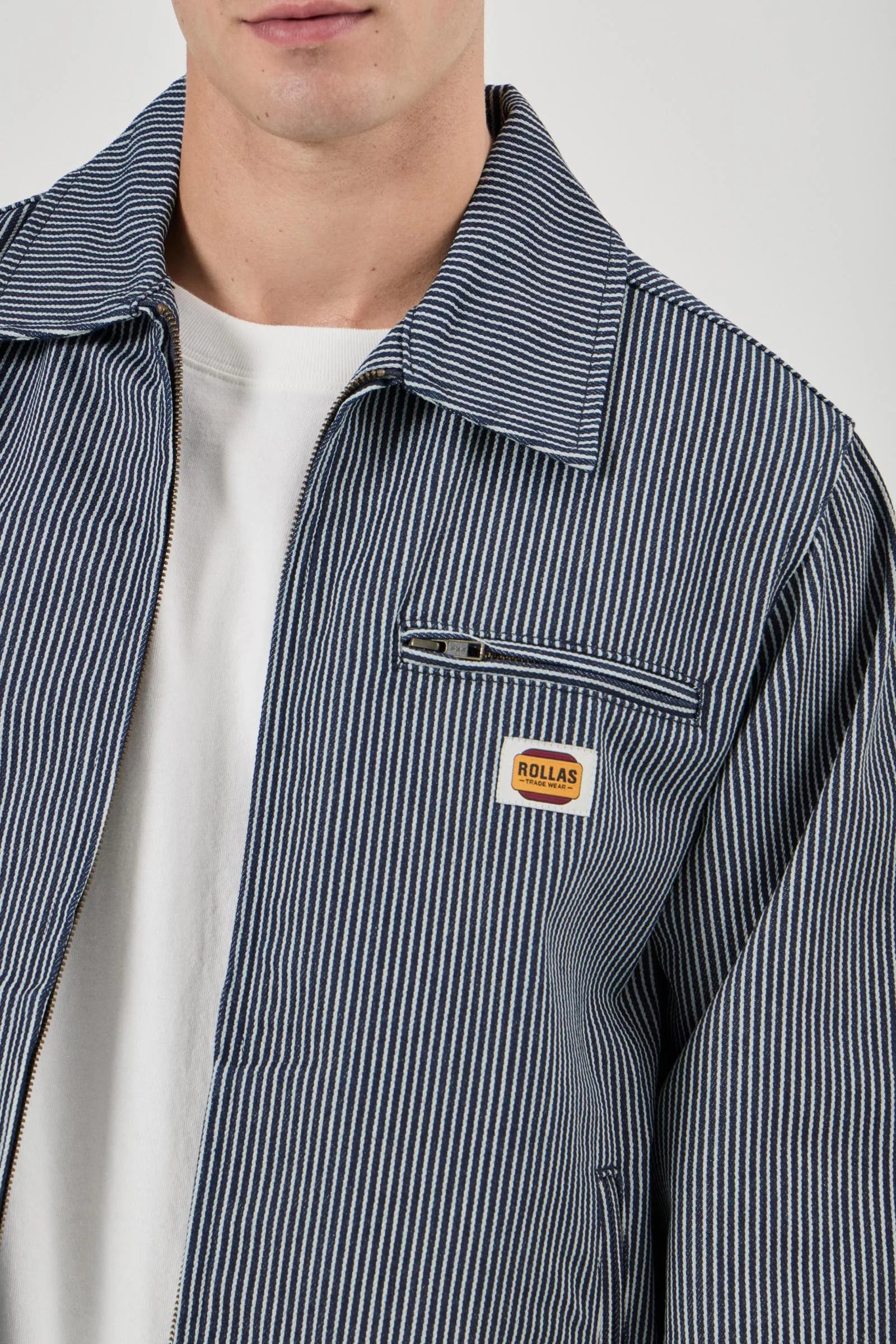 Close-up of a person wearing a striped jacket with a brand logo on a light gray background