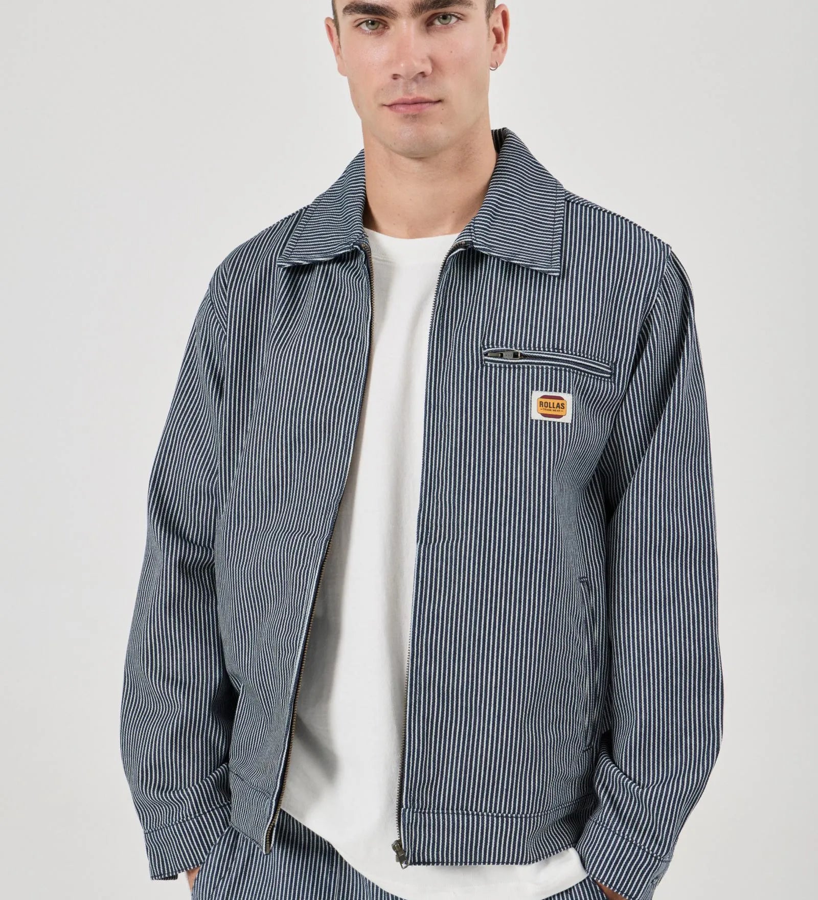 Man wearing a blue striped jacket with a visible brand logo on a white background