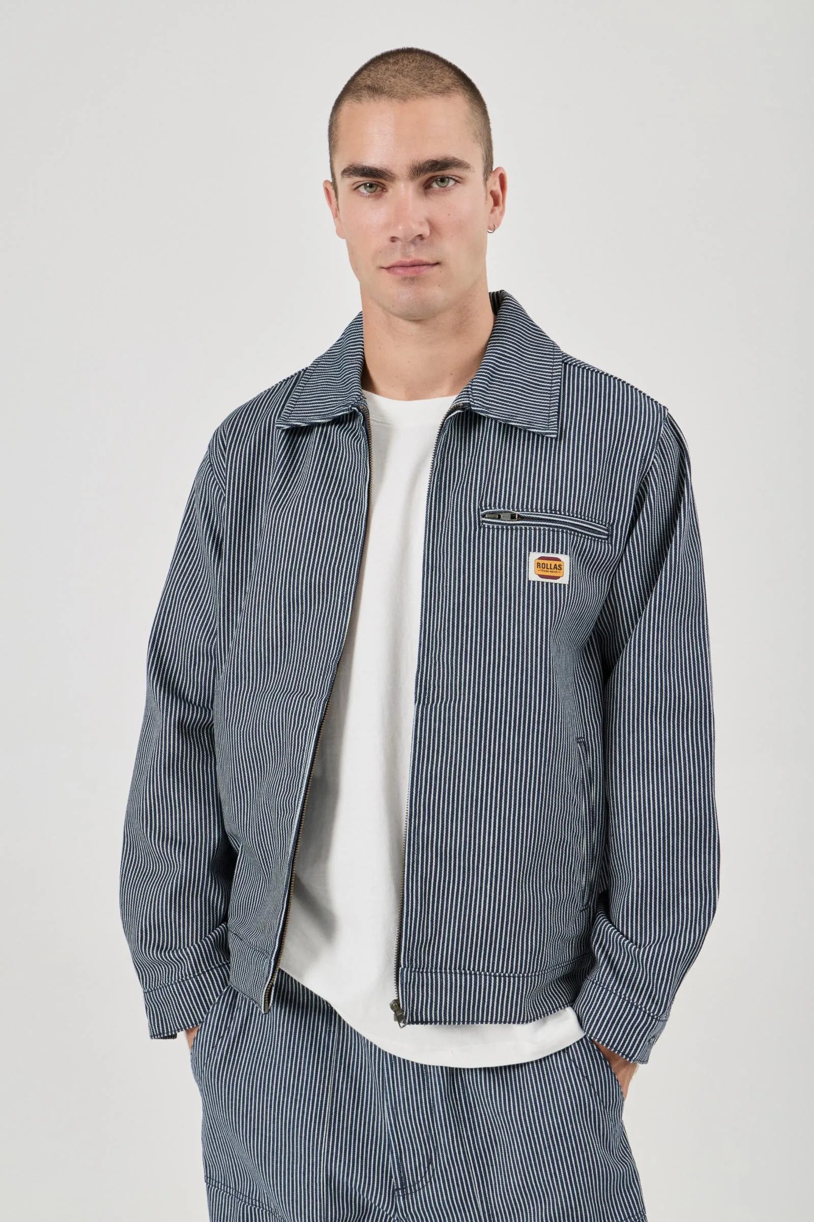 Man wearing a blue striped jacket with a visible brand logo on a white background