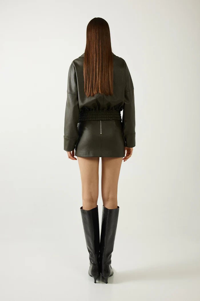 Person wearing a green leather outfit with black boots on a white background