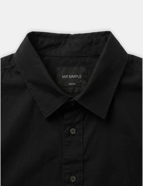 Close-up of a black long-sleeve button-down shirt collar with a visible MR SIMPLE neck label, on a light gray background.