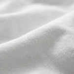 A close-up of soft white fabric with gentle folds and a smooth texture.