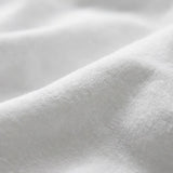 A close-up of soft white fabric with gentle folds and a smooth texture.