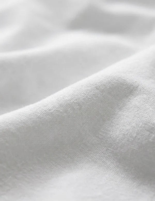 A close-up of soft white fabric with gentle folds and a smooth texture.