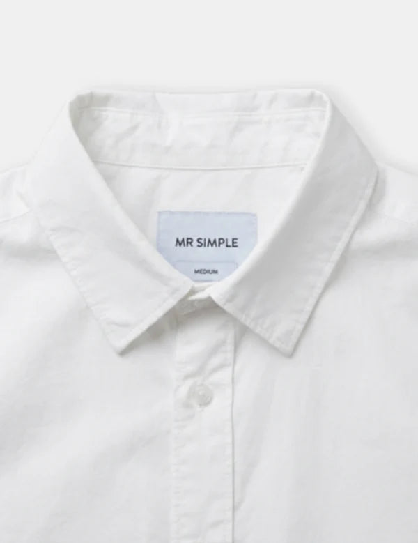 Close-up of a white long-sleeve button-down shirt collar with a light blue interior label reading 'MR SIMPLE' and 'MEDIUM'.