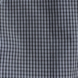 A close-up of a black and white checkered fabric pattern, showing the fine grid texture of the plaid.