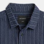 Close-up of a navy blue button-down shirt with thin white vertical pinstripes, featuring a black neck label that reads 'MR SIMPLE'.