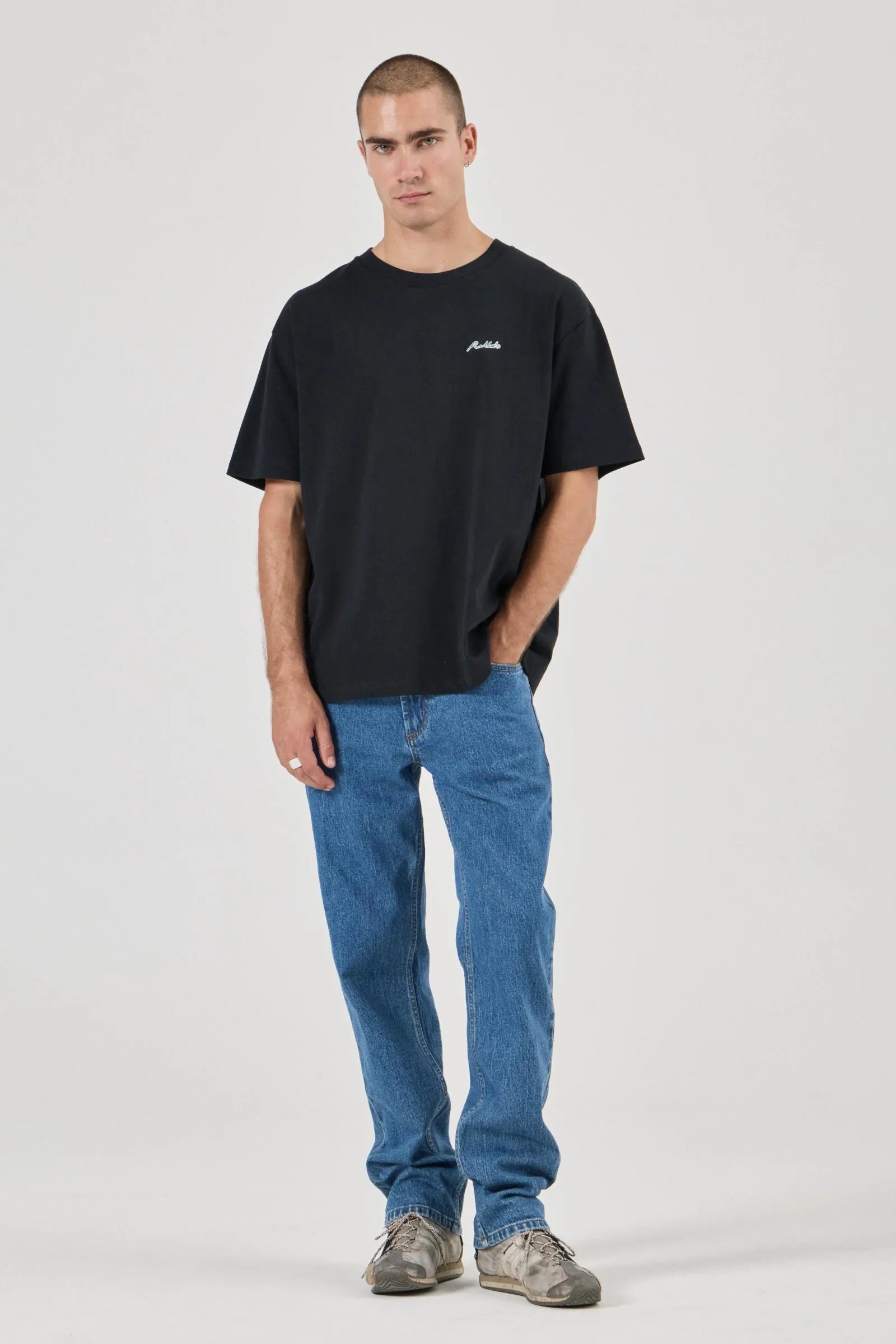 Man wearing a black t-shirt and blue jeans on a white background