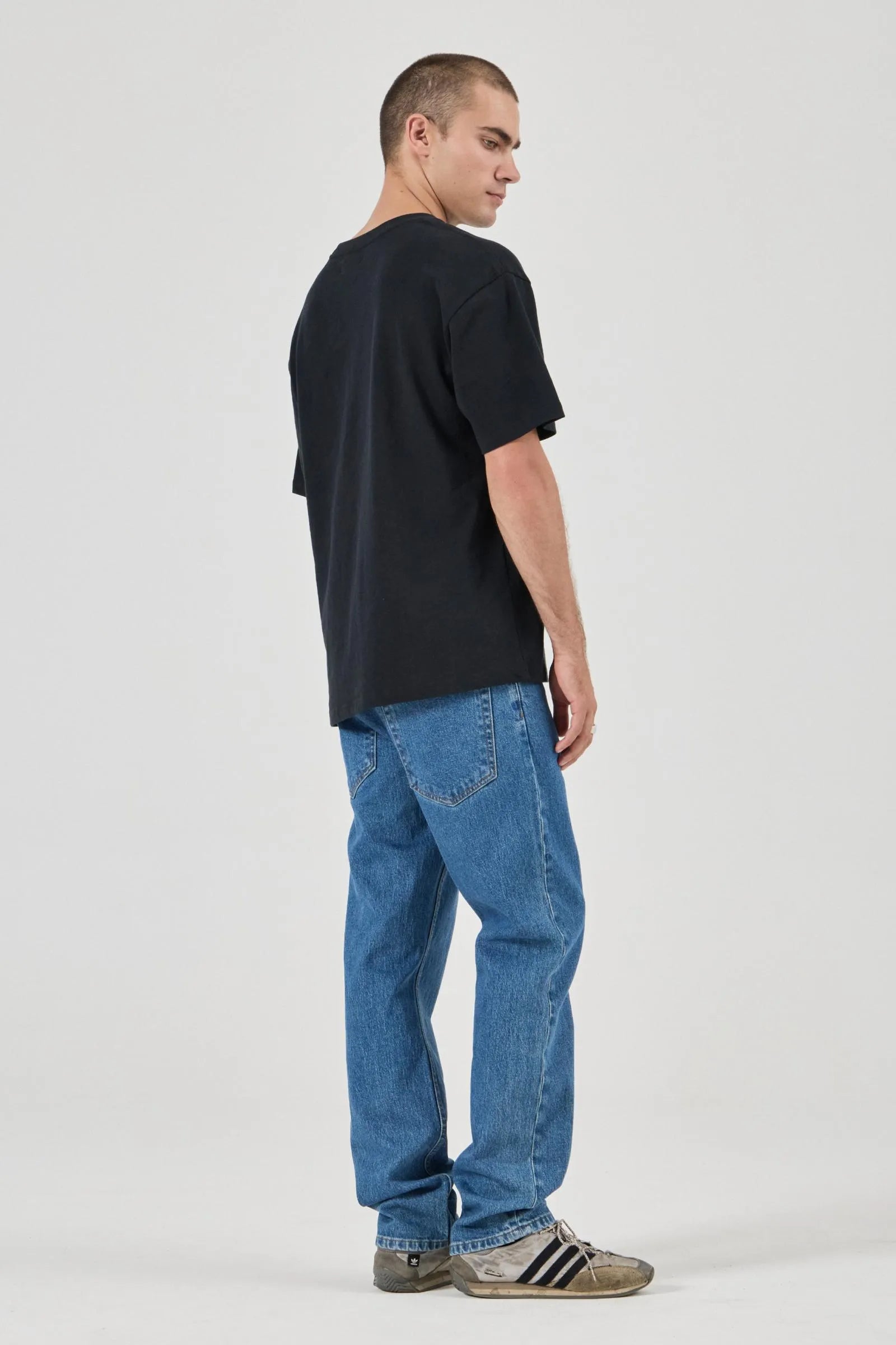 Person wearing a black t-shirt and blue jeans on a white background