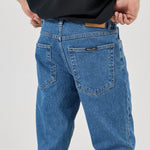Person wearing blue jeans and a black shirt on a white background