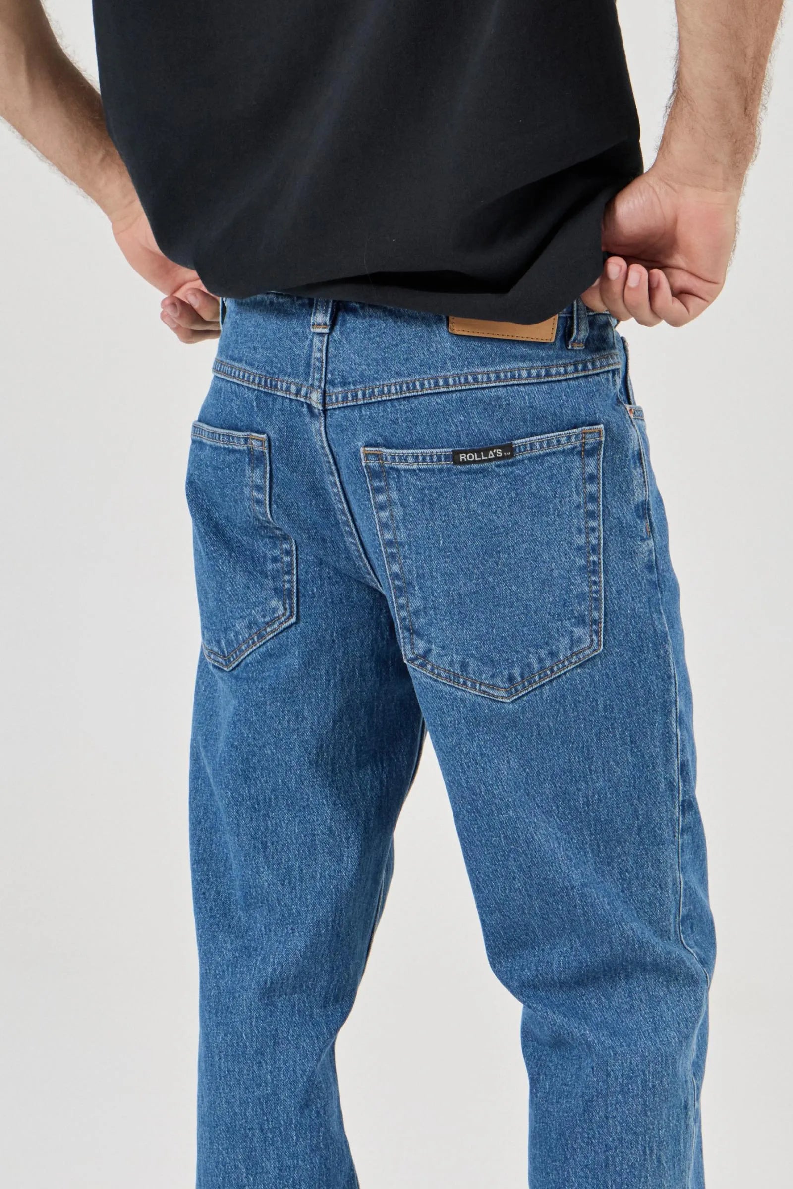 Person wearing blue jeans and a black shirt on a white background
