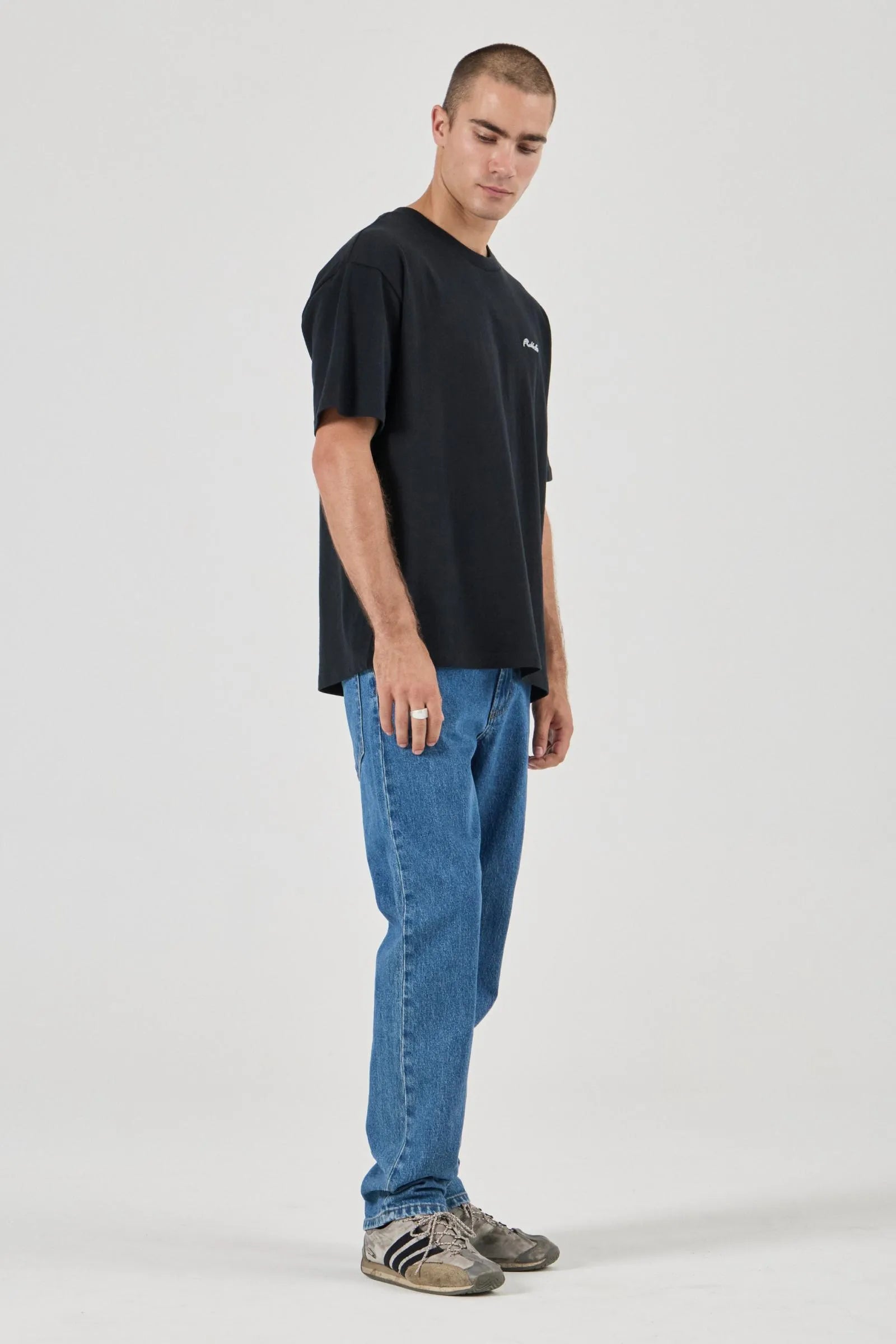 Man wearing a black t-shirt and blue jeans on a white background