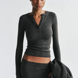 Woman wearing a gray long-sleeve top and pants against a white background