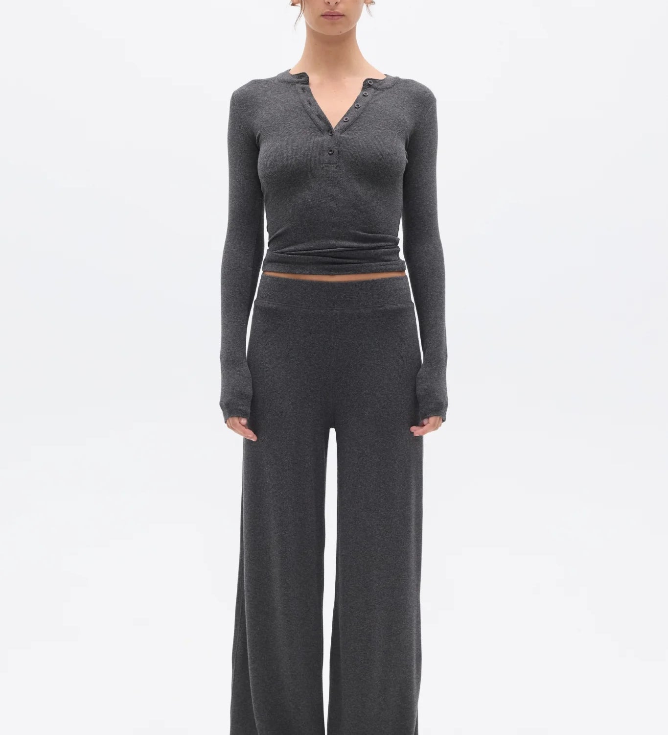 Woman wearing a gray long-sleeve top and wide-leg pants on a white background