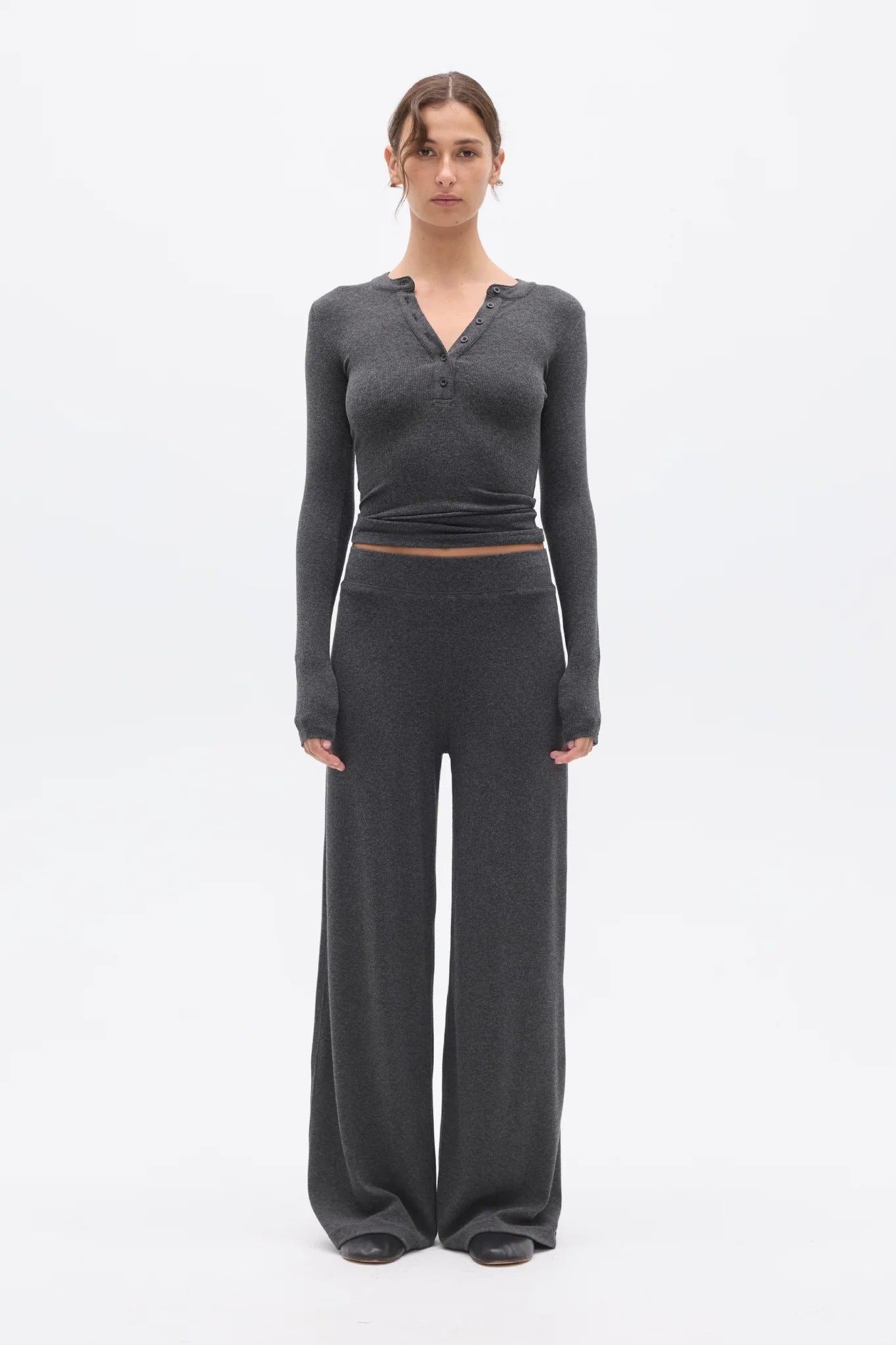 Woman wearing a gray long-sleeve top and wide-leg pants on a white background