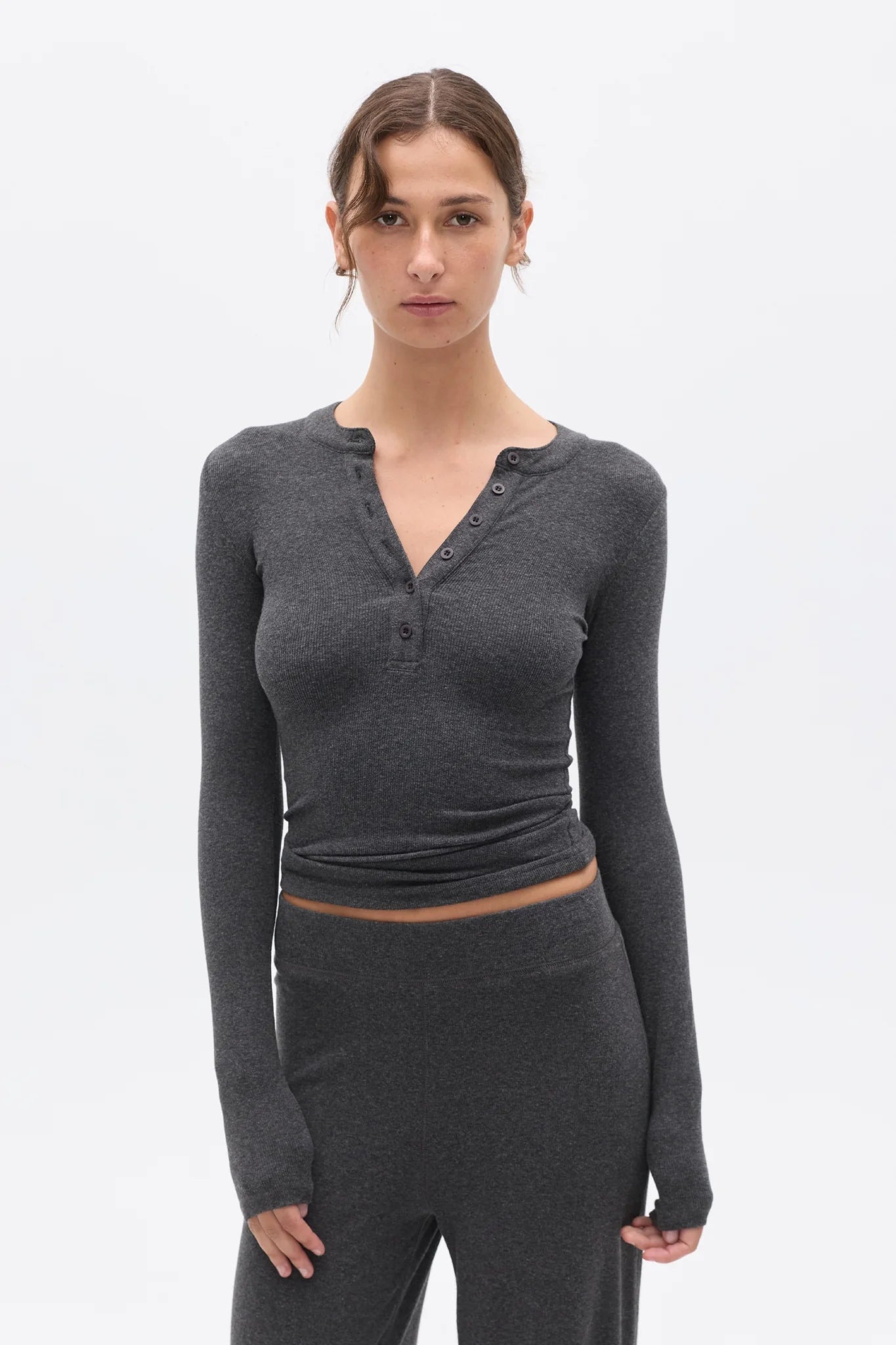 Woman wearing a dark gray long-sleeve top and pants on a white background