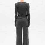 Person wearing a dark gray long-sleeve top and wide-leg pants on a white background