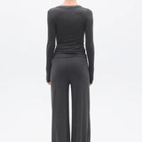 Person wearing a dark gray long-sleeve top and wide-leg pants on a white background