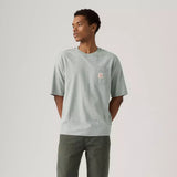 Man wearing a light gray t-shirt with a pocket on a plain background