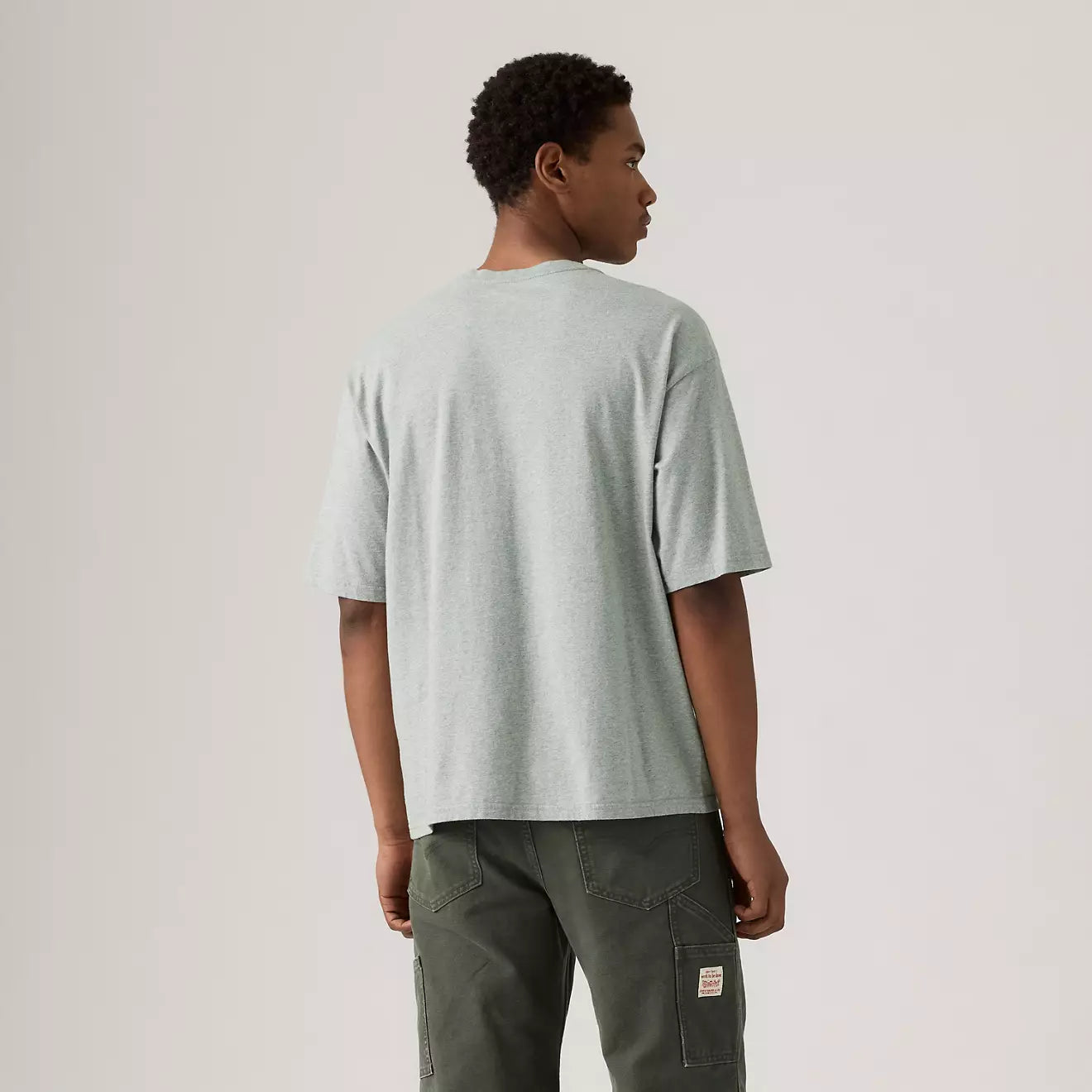 Person wearing a light gray t-shirt and dark green pants on a plain background