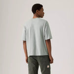 Person wearing a light gray t-shirt and dark green pants on a plain background