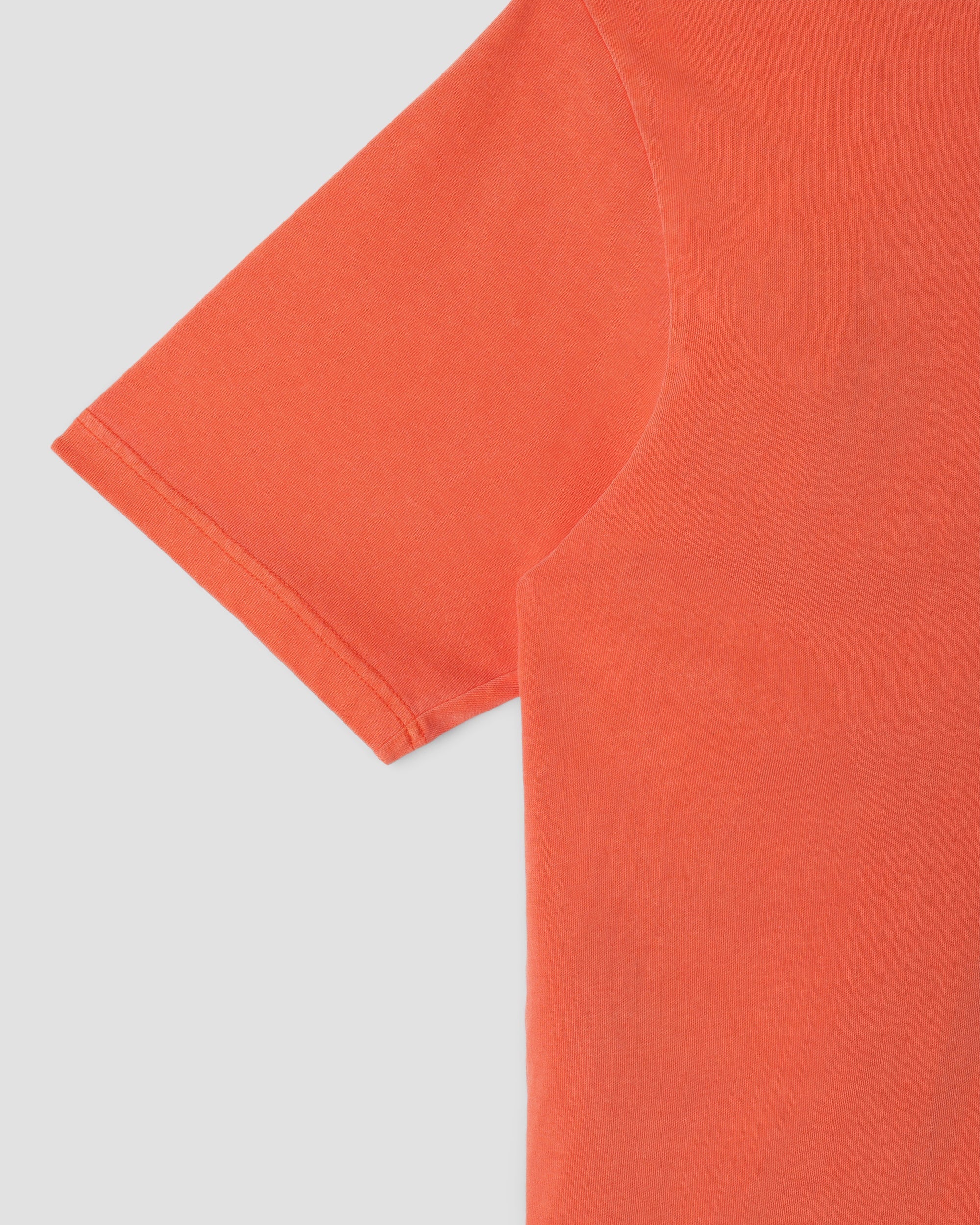 Close-up of an orange t-shirt on a light gray background