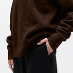 Brown sweater worn by a person on a white background