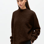 Woman wearing a brown sweater on a white background