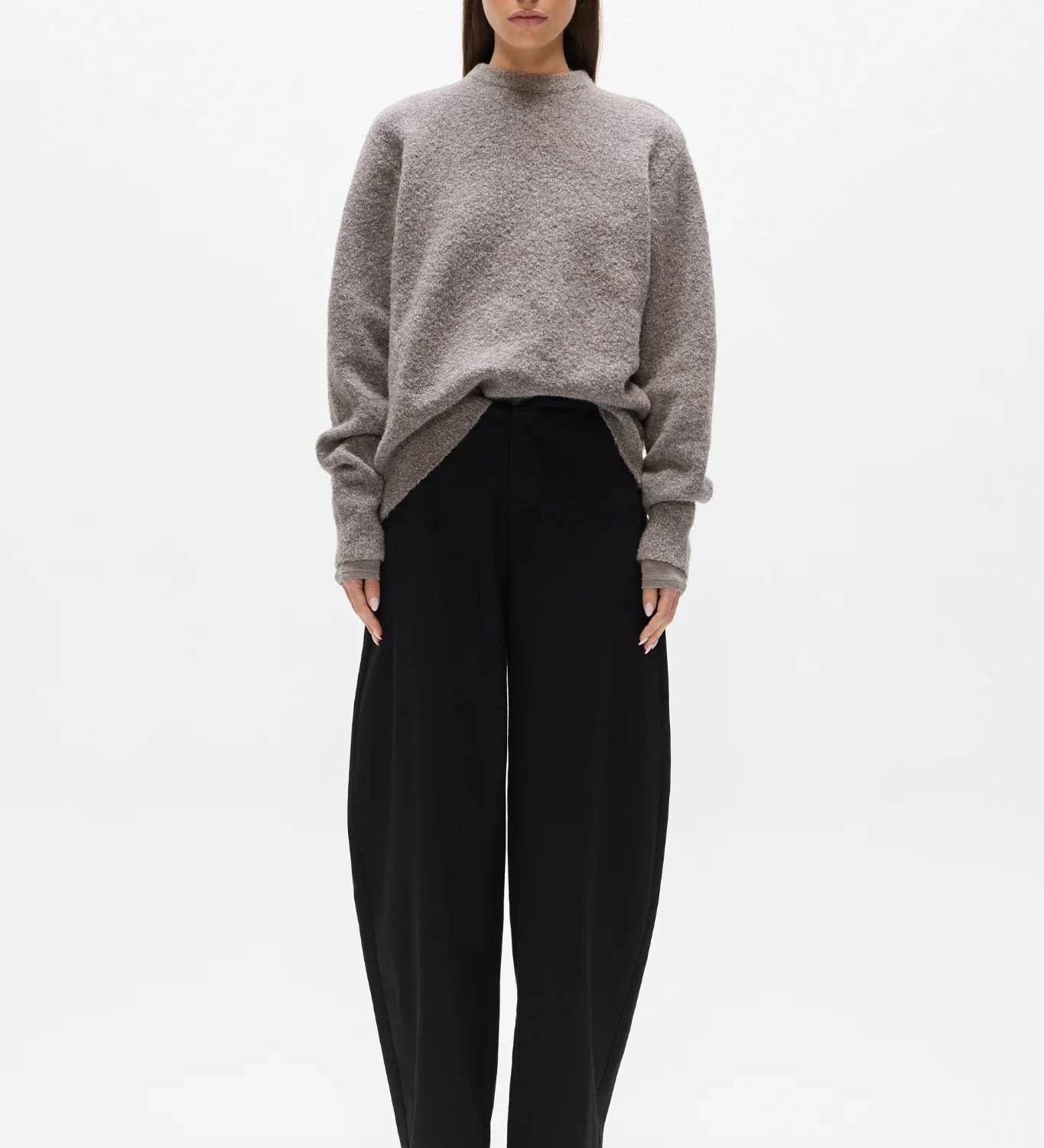 Woman wearing a gray sweater and black pants on a white background