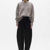 Woman wearing a gray sweater and black pants on a white background