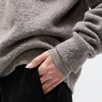 Person wearing a gray fleece jacket with a blurred background