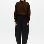 Woman wearing a brown sweater and black pants on a white background