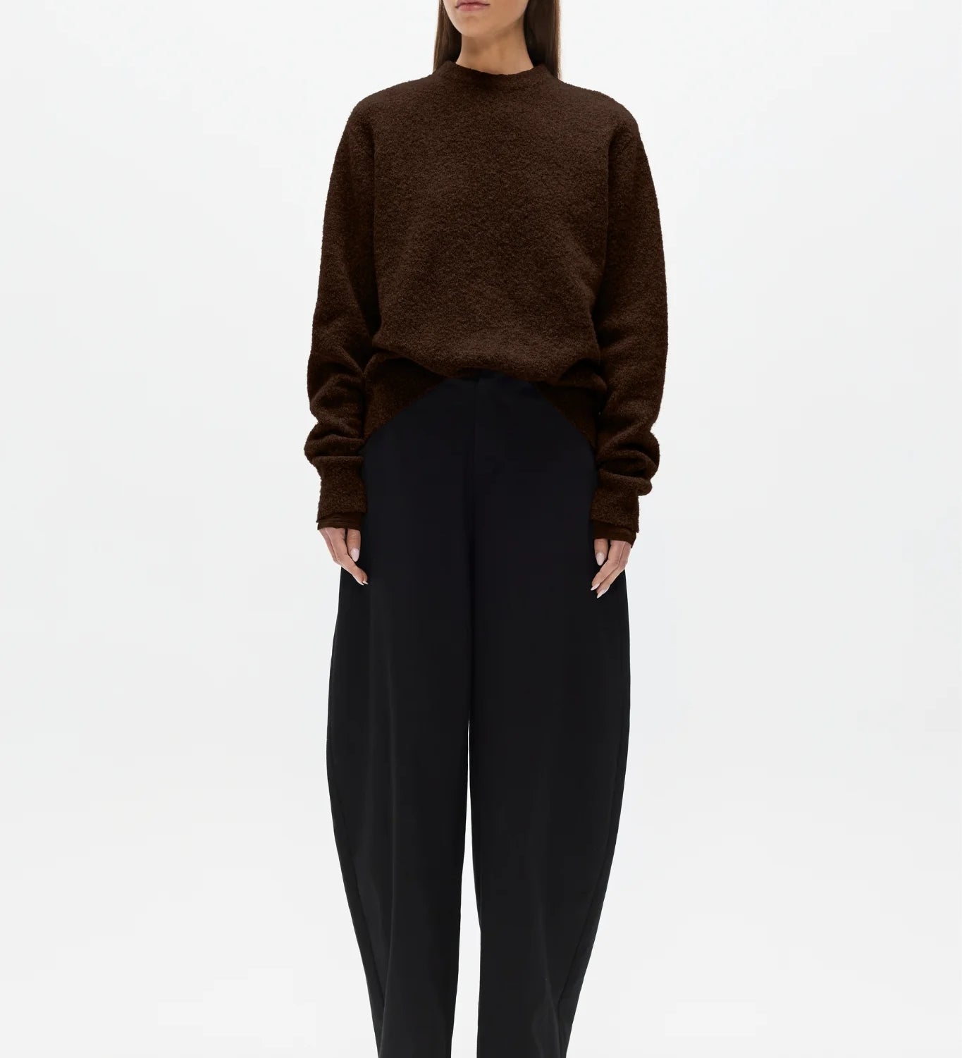 Woman wearing a brown sweater and black pants on a white background