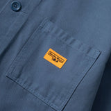 Close-up of a blue shirt with a yellow label on the chest pocket.