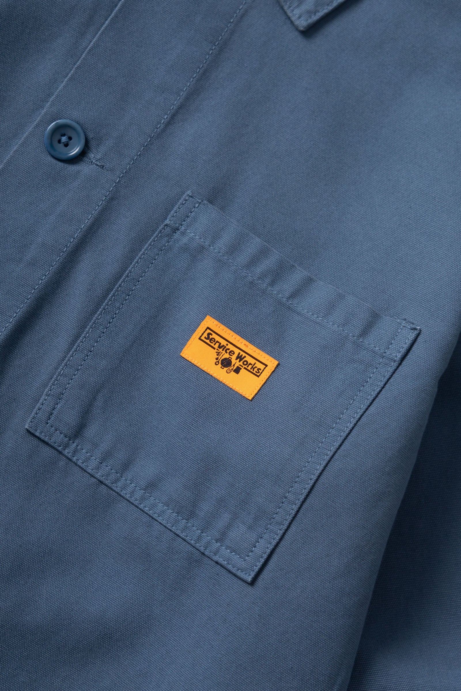 Close-up of a blue shirt with a yellow label on the chest pocket.