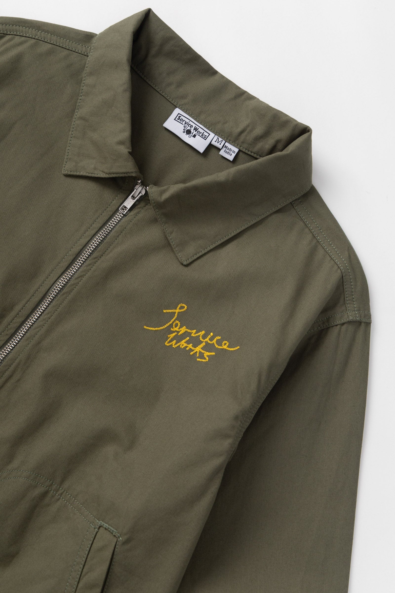 Green jacket with yellow embroidery and a brand label on a white background