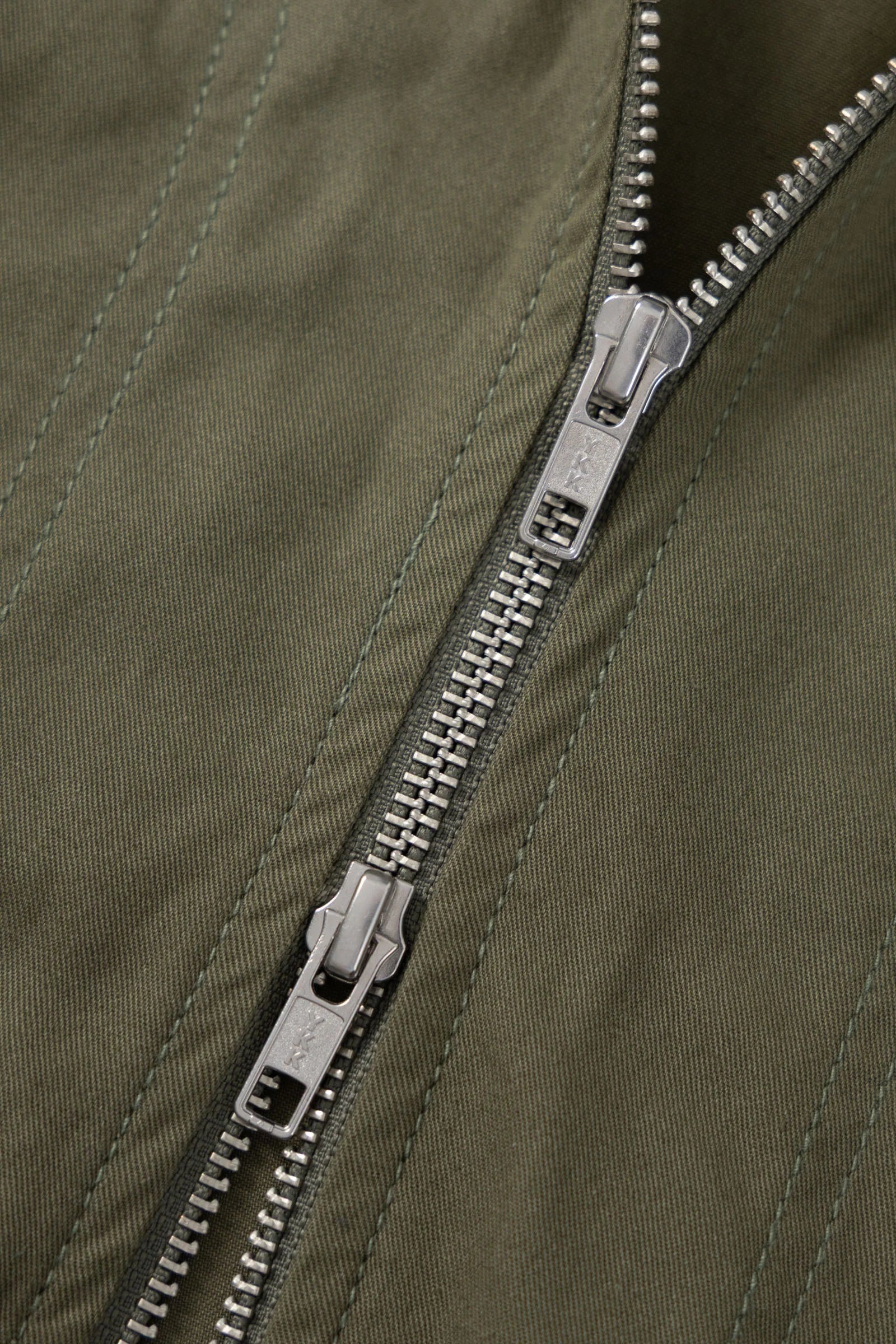 Close-up of a silver zipper on a green jacket