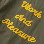 Green jacket with yellow text 'Work And Pleasure' on a dark background
