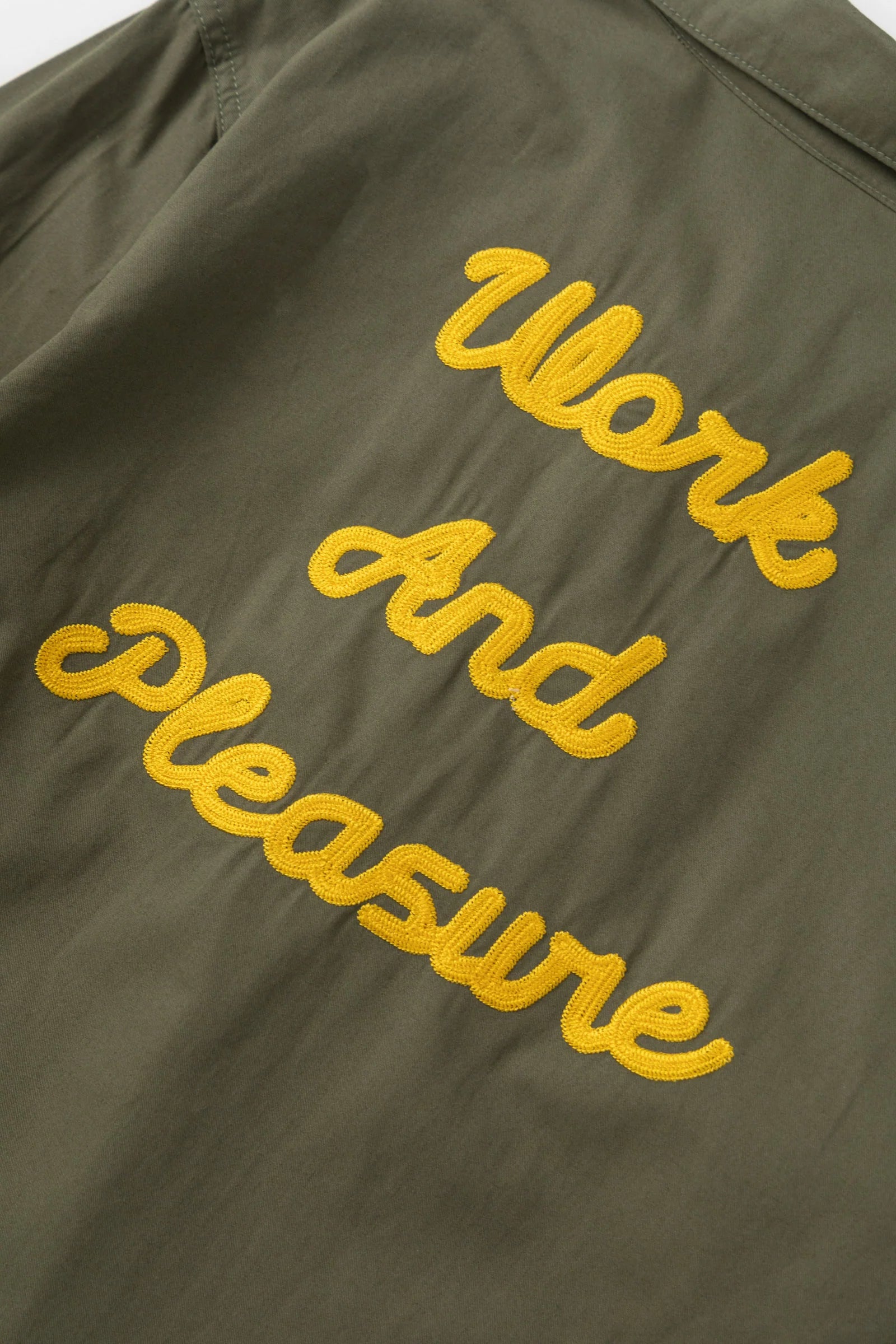 Green jacket with yellow text 'Work And Pleasure' on a dark background