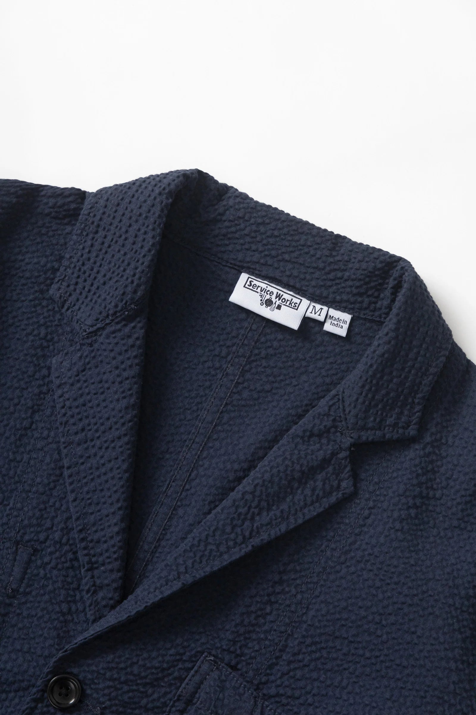 Navy textured jacket with a brand label on a white background