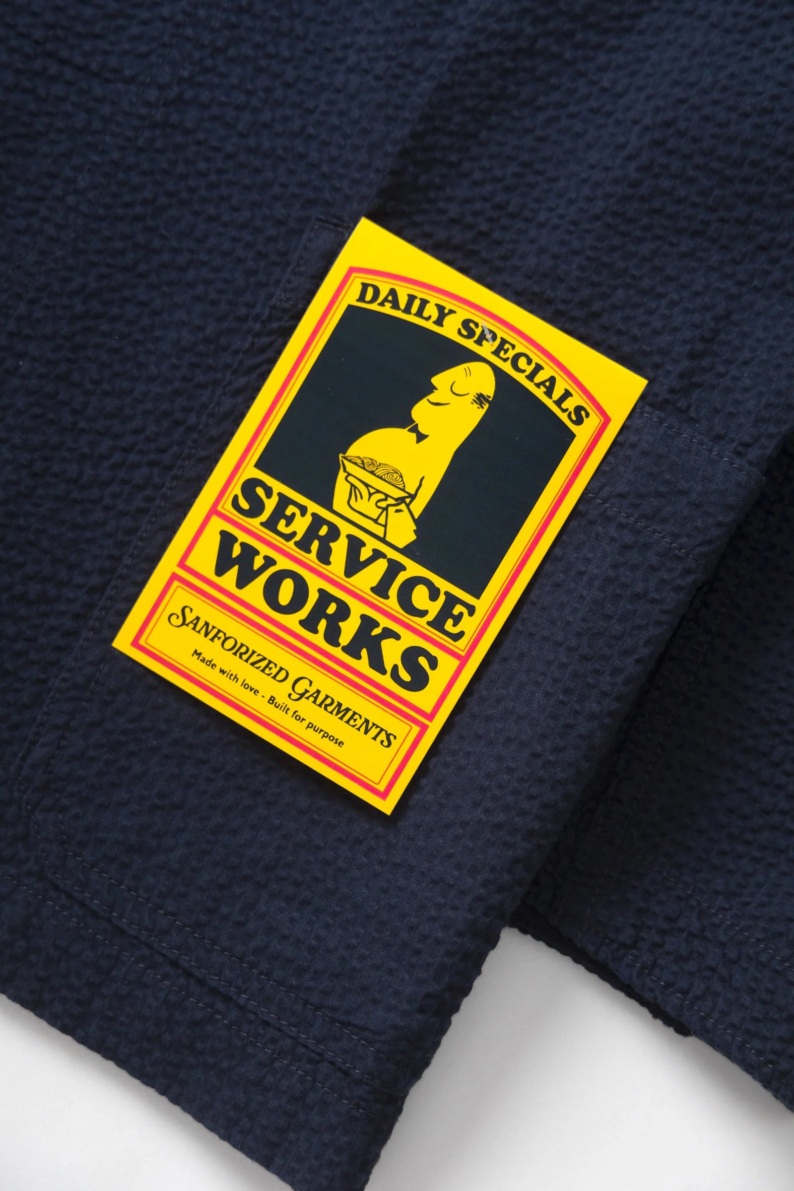 Navy blue fabric with a yellow 'Service Works' label on a white background